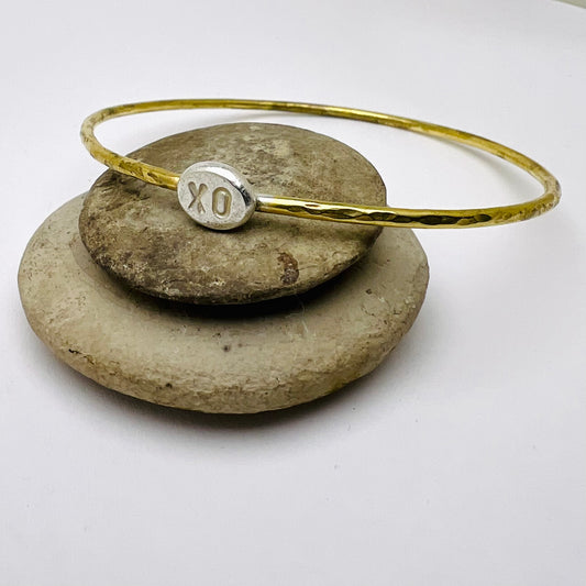 Brass bracelet with a silver charm on a stack of stones