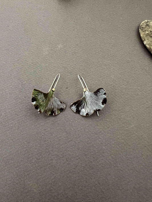Copper ginkgo leaf earrings with sterling silver ear wires on a gray surface
