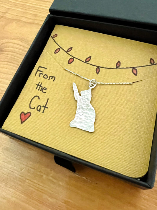 Handmade hammered silver cat pendant, front view in box.
