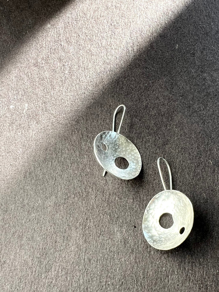 Pair of silver earrings on a dark surface
