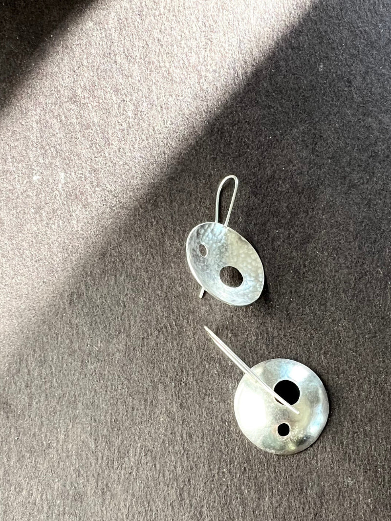 Pair of silver earrings on a dark surface