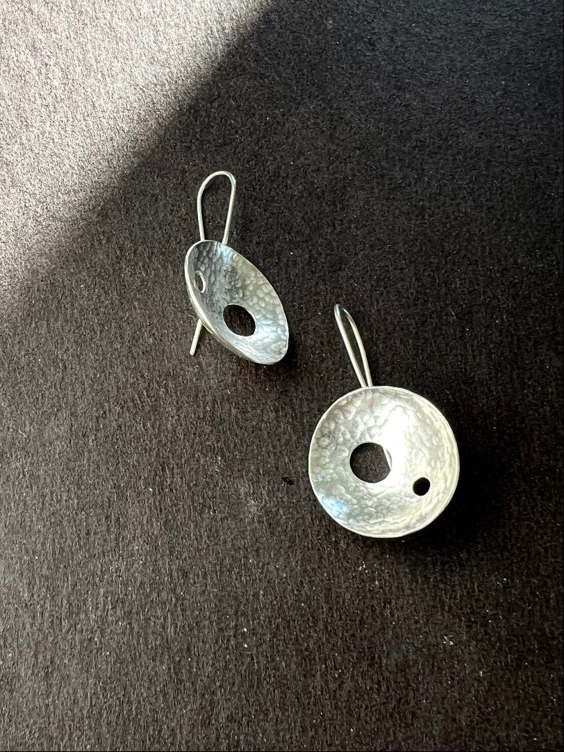 Pair of hammered silver dome earrings on a dark surface