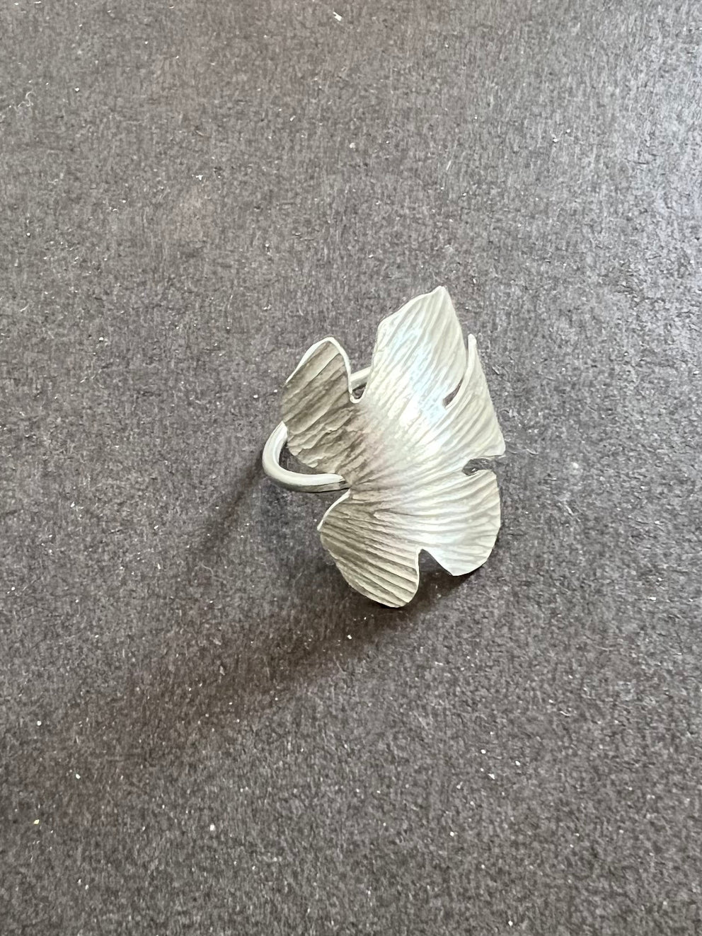 Silver leaf-shaped ring on a gray surface