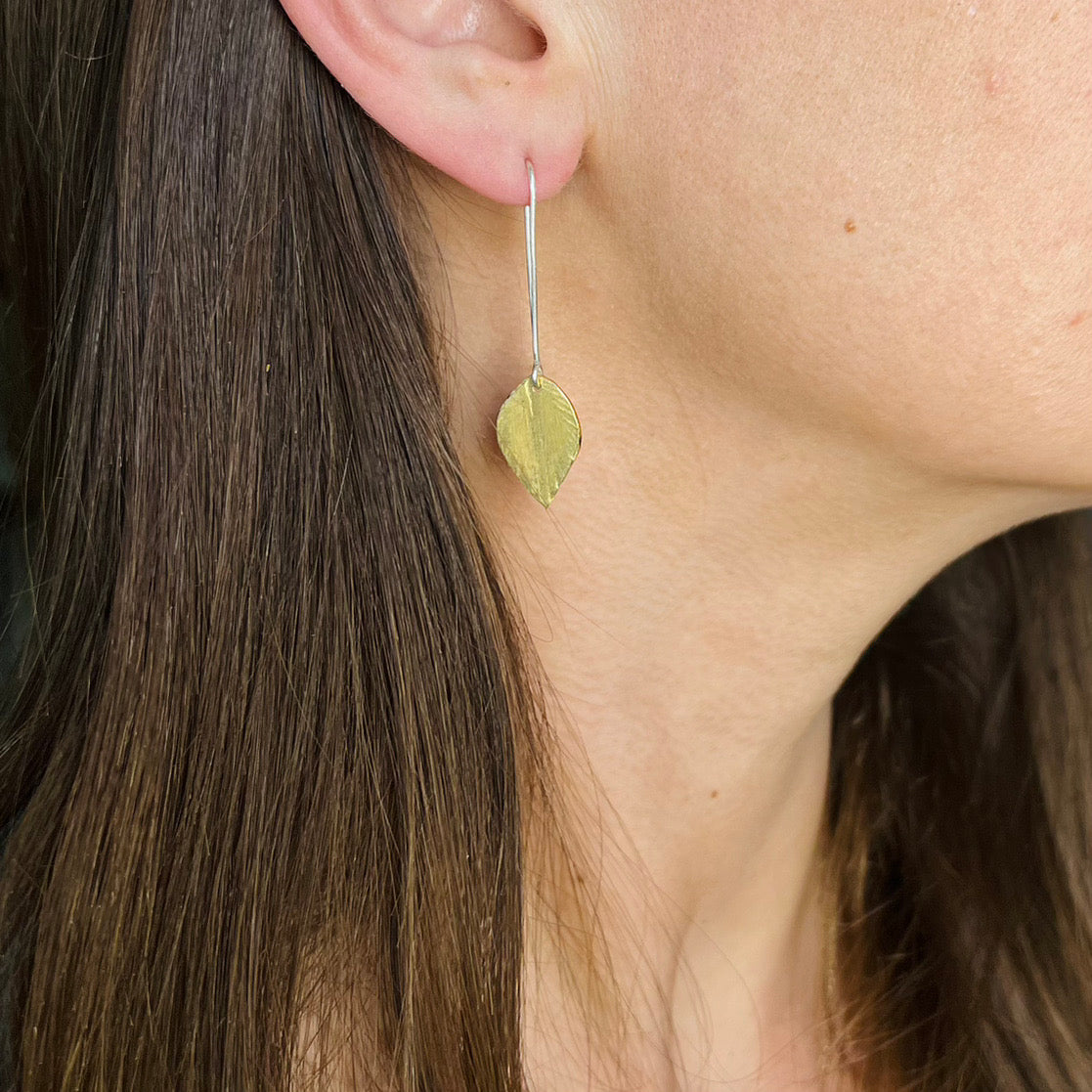 long silver ear wire with a brass leaf, shown on woman.