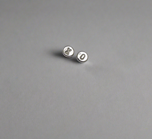 Pair of XO silver earrings on a gray background