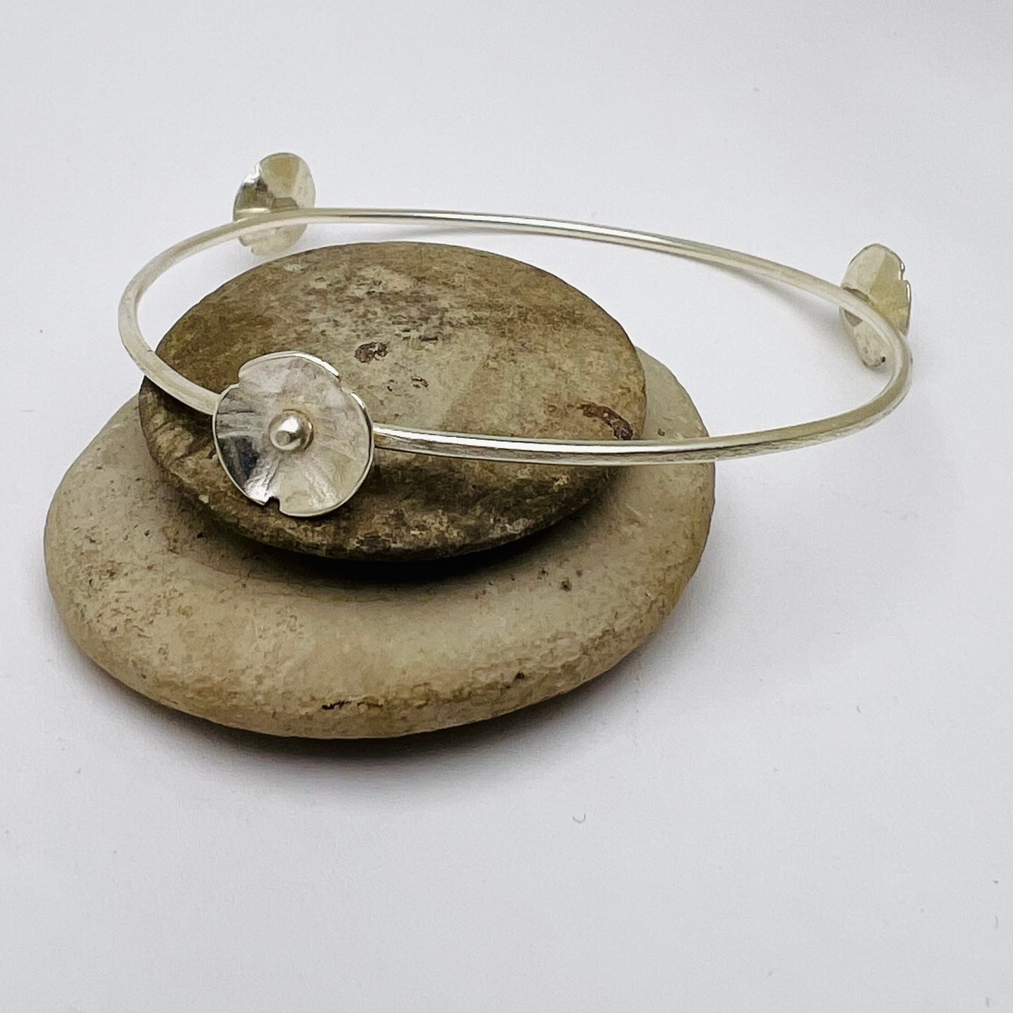 Silver bracelet with a round silver charm on a white background