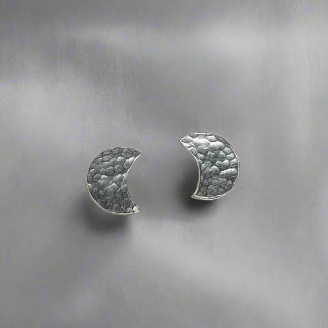 Pair of silver half-moon earrings on a textured gray background