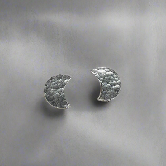 Pair of silver half-moon earrings on a textured gray background