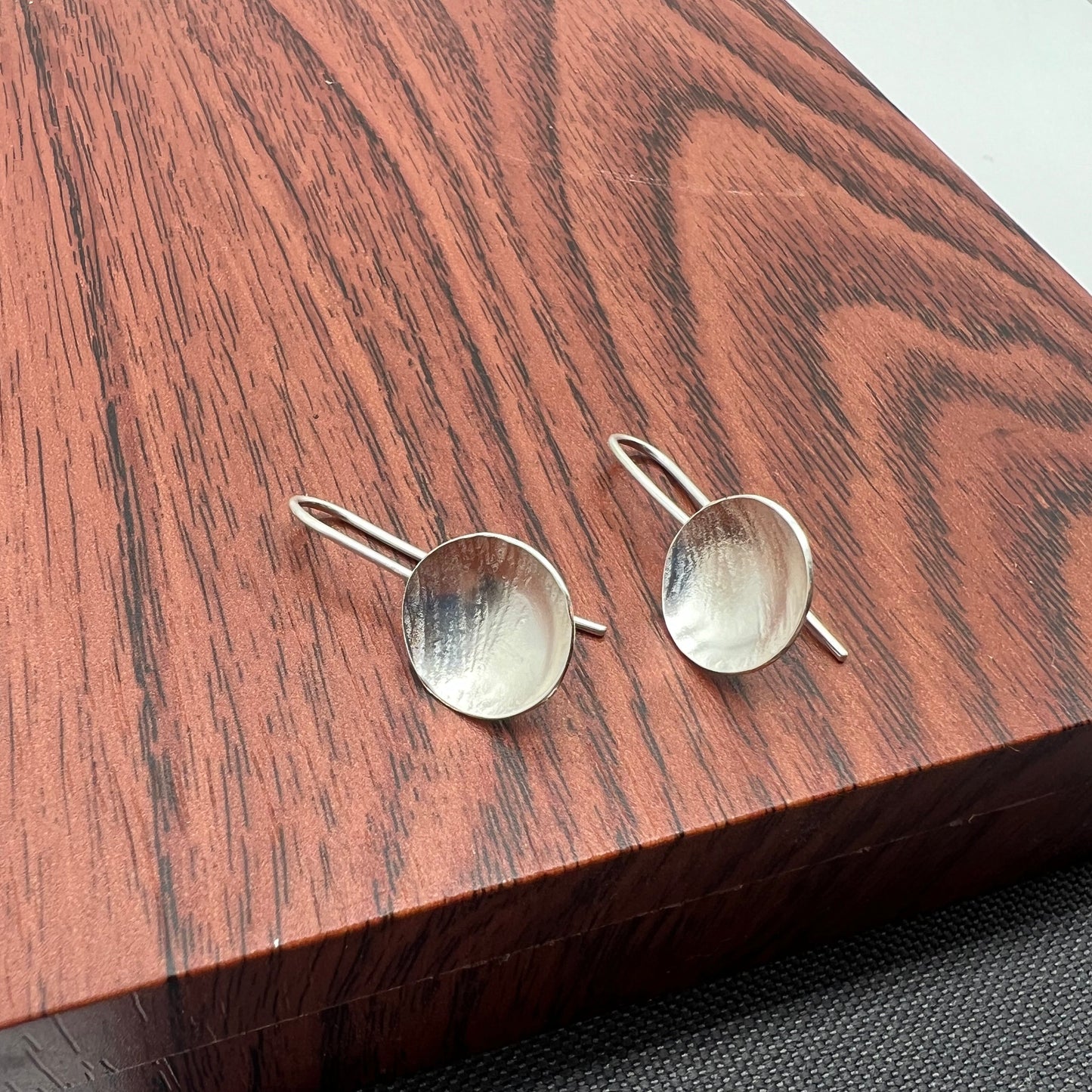 Silver dome earrings on a wood background.